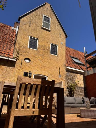 a wooden chair sitting in front of a building at Het Poort'vakantie'Huis in Grou
