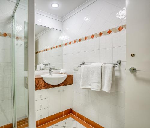 a white bathroom with a sink and a shower at Xanadu Resort in Gold Coast
