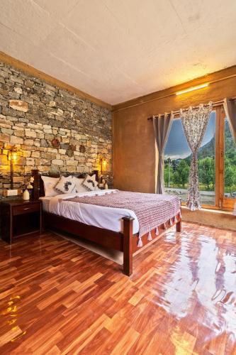 a bedroom with a bed and a stone wall at Himalayan Willow in Gushaini