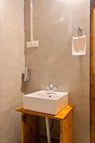 a bathroom with a white sink on a wooden table at Himalayan Willow in Gushaini