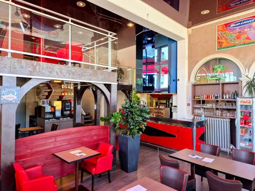 un restaurant avec des chaises et des tables rouges ainsi qu'un bar dans l'établissement Arche Hotel, à Vierzon