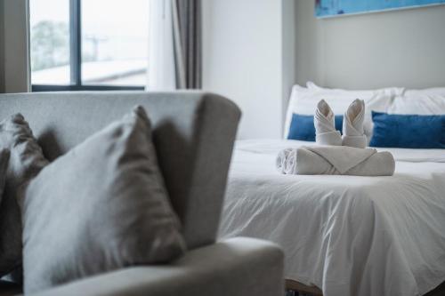 a white bed with a chair and a stuffed animal on it at C176 Diamond Paradise Getaway Condo Phuket in Bang Tao Beach