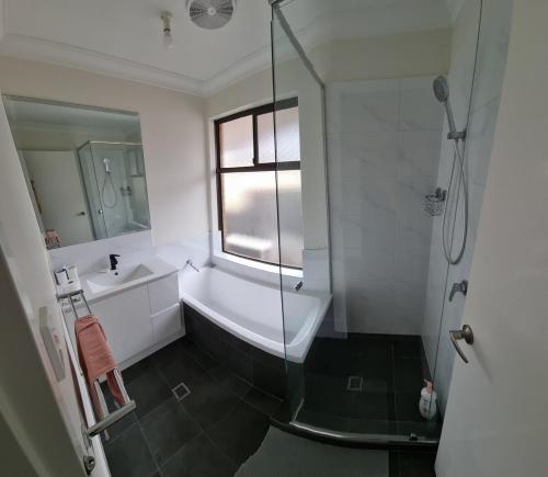 a bathroom with a shower and a tub and a sink at check in 11am check out 2pm in Riverton in Perth