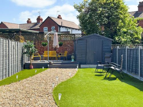 a small garden with a black shed and grass at 5-Bed Family & Group Stay Near Cricket Ground in Worcester