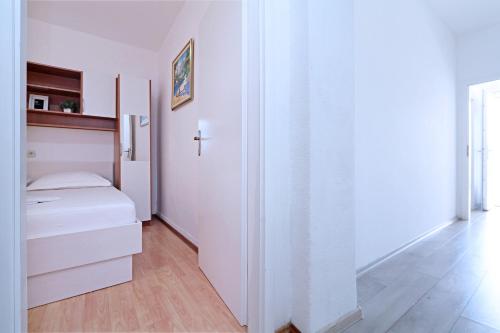 a white room with a bed and a cross on the wall at Apartments Villa Flamingo in Makarska