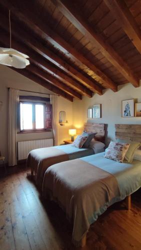two beds in a room with wooden ceilings at Posada La Dalia in Castillo-Pedroso