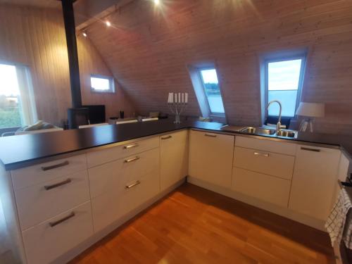 a kitchen with white cabinets and a sink and windows at Kuvågen 23 in Vågenes