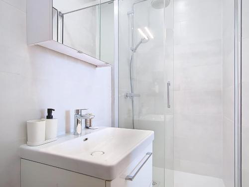 a white bathroom with a sink and a shower at Suite Evasion - Bel Appartement in Argenteuil