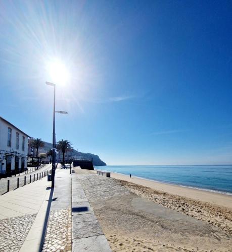 a beach with a light pole and the ocean at Apartamento Armanbel in Sesimbra