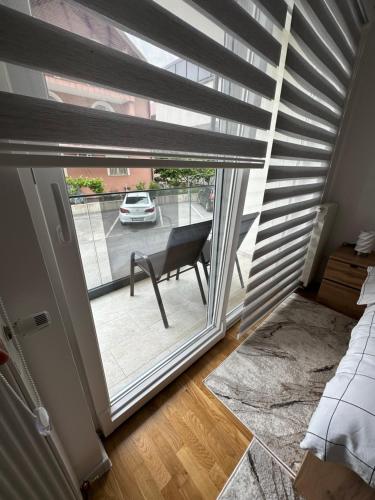 a room with a window with a chair and a car outside at ZORA apartmani Sarajevo in Sarajevo