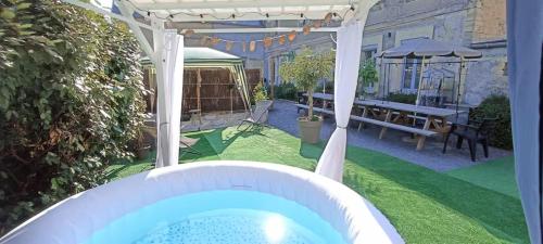 une cour avec un bain à remous et une pergola dans l'établissement Séjour familial haut de gamme spa et confort près des plages du Débarquement, à Sommervieu