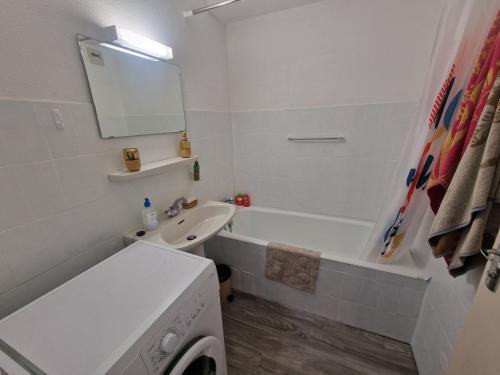 La salle de bains blanche est pourvue d'un lavabo et d'une baignoire. dans l'établissement Appartement entre mer et montagne, à La Celle-sous-Gouzon