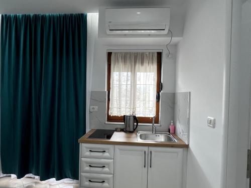 a kitchen with a sink and a blue curtain at Guesthouse Mance in Ksamil