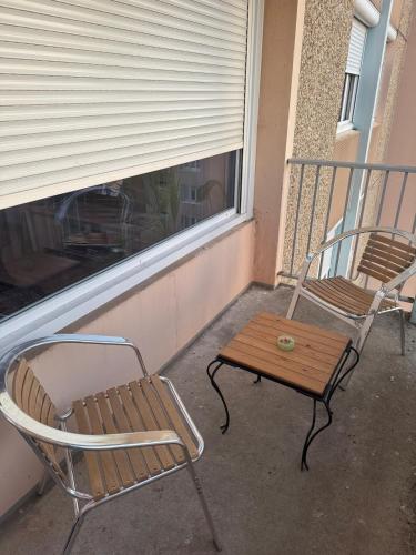 - deux chaises et une table sur une terrasse couverte avec une fenêtre dans l'établissement Charming studoi kuilopil, à Chalon-sur-Saône