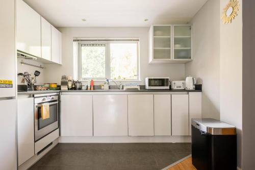 a kitchen with white cabinets and a window at Lovely Harbourside Apartment with Free Parking in Bristol