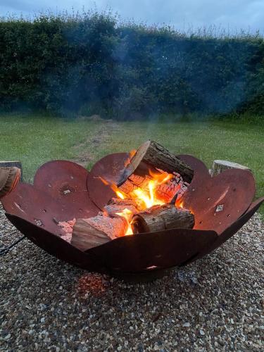 a fire pit with flames in the middle of a field at The Skye Yurt in Messing