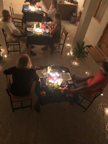 a group of people sitting around a table with lit candles at Leaf fish guesthouse Maldives in Keyodhoo