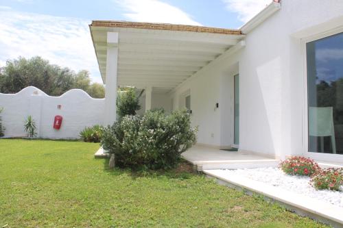 a white house with a white wall and a yard at LIDO DEL FARO in Olbia