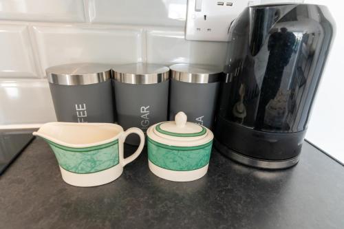 three coffee cups sitting on a counter next to a coffee maker at Comfortable Stays - Shirley, Solihull in Birmingham