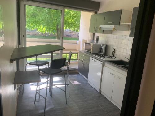 une petite cuisine avec une table et des chaises ainsi qu'une fenêtre dans l'établissement Entire F2 apartment feveretere, à Chalon-sur-Saône
