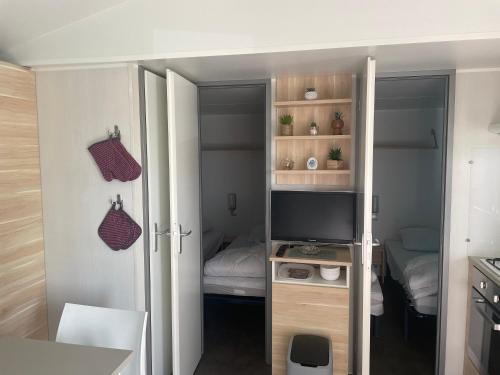 a small room with a television and a bedroom at Mobilhome in Litteau