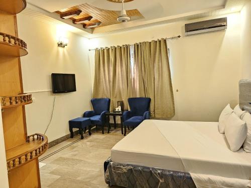 a hotel room with a bed and chairs and a tv at Butt Lodges 2 in Islamabad