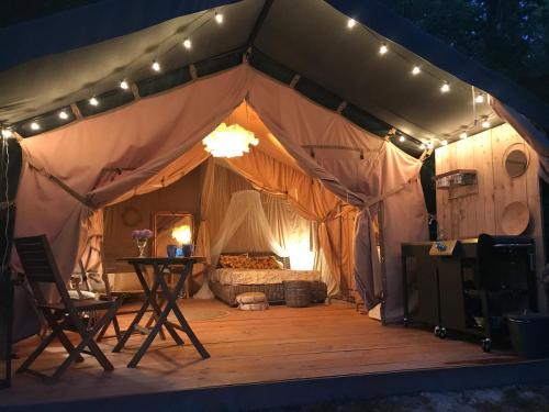 une tente avec un lit et une table. dans l'établissement Les Toiles de La Tortillère tentes luxes safari lodge glamping insolite, à Marçay