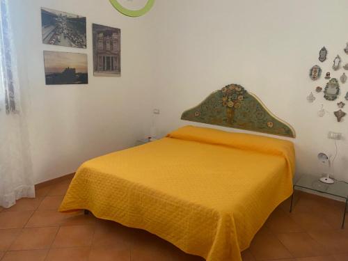 a bedroom with a bed with a yellow blanket on it at Casa Ale in Favignana