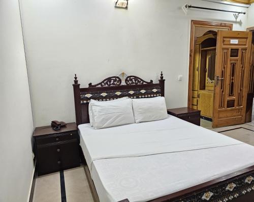 a bedroom with a large white bed with a wooden headboard at Butt Lodges 2 in Islamabad