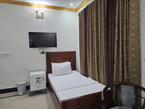 a small bedroom with a bed and a tv at Butt Lodges 2 in Islamabad