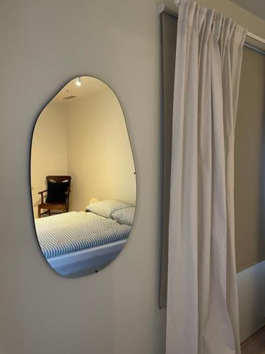 a mirror in a room with a bed and a chair at Central apt near beach and city life in Kristiansand