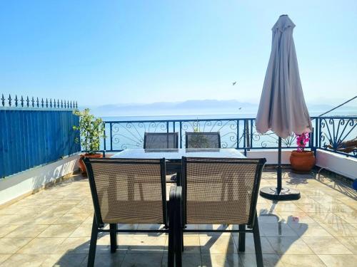 a table and chairs on a balcony with an umbrella at Alkyone in Petalidhion