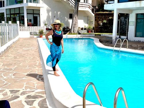 a woman standing on the edge of a swimming pool at Las Olas Suite - Bajamar in Bajamar