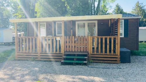 a tiny house with a porch and a gate at Chez Nathalie mobil home chauffé et climatisé in Boofzheim