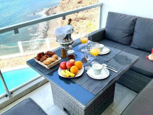 a table with a tray of fruit and bread on a balcony at Las Olas Suite - Bajamar in Bajamar