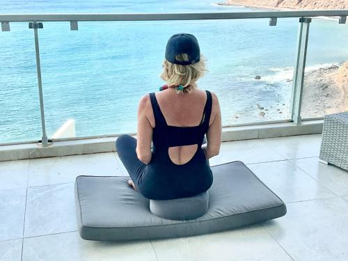 a woman sitting on a pillow looking out at the ocean at Las Olas Suite - Bajamar in Bajamar