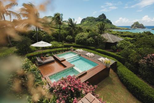 an aerial view of a pool with chairs and an umbrella at Pousada Maravilha in Fernando de Noronha