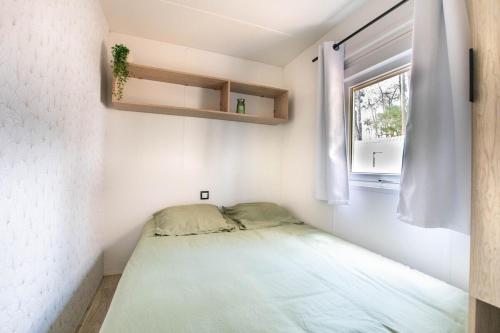 Un dormitorio pequeño con una cama y una ventana. en Luma Lodge, en Seignosse