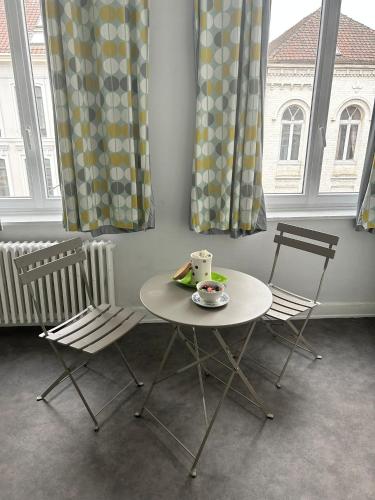 une table et des chaises dans une pièce avec des fenêtres dans l'établissement Suite Fleurus, à Lille