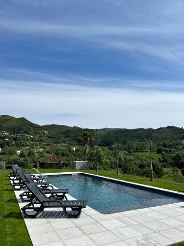 a swimming pool with lounge chairs and a view of the mountains at Quinta da Ponte by Gerês Casas in Terras de Bouro