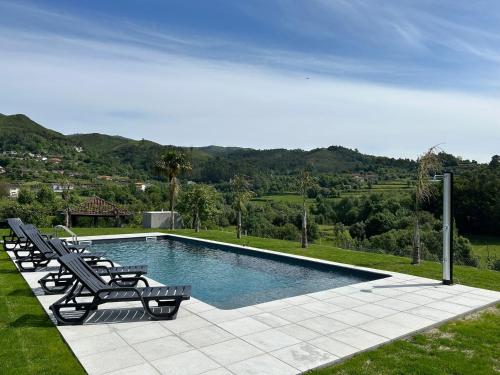 a swimming pool with two lounge chairs next to it at Quinta da Ponte by Gerês Casas in Terras de Bouro