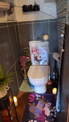 une salle de bain avec toilettes avec une affiche de film dans l'établissement Maquis Foch House With Parking and Garden Near Town, à Ruffec