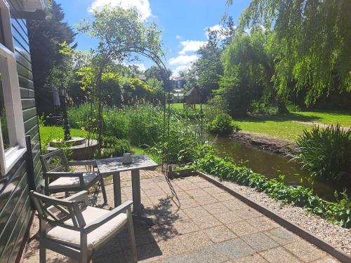 a patio with two chairs and a table next to a river at B&B Saense huisje in Assendelft
