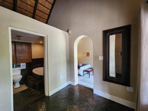 Un pasillo con un baño con lavabo y espejo. en Leopard Rock Guest Lodge, en Mica