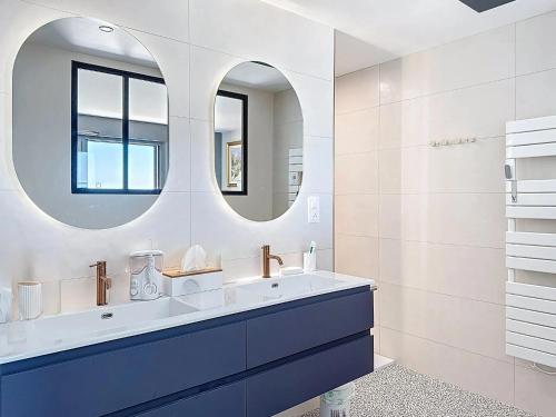une salle de bain avec un lavabo et deux miroirs dans l'établissement Trois Plages Pleine Mer, à Royan