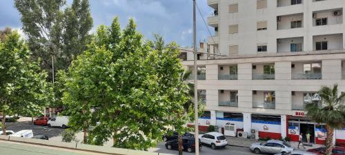 a large white building with cars parked in a parking lot at K&M apartment in Polisi i Vogël