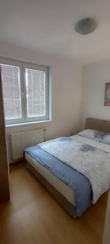 a bedroom with a bed and two windows at Apartman Rubin20 in Doboj