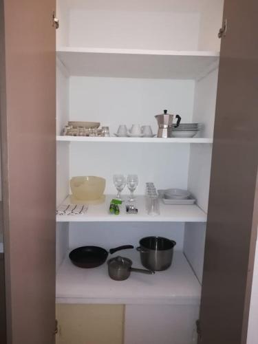 a kitchen with white shelves with pots and pans at Appartamenti Praia Estoril, Sal Rei, Boa Vista in Sal Rei
