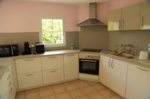 une cuisine avec des armoires blanches, un évier et une fenêtre dans l'établissement Maison de vacances à Angles, à Angles