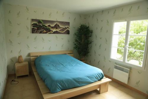 une chambre avec un lit avec des draps bleus et une fenêtre dans l'établissement Maison de vacances à Angles, à Angles